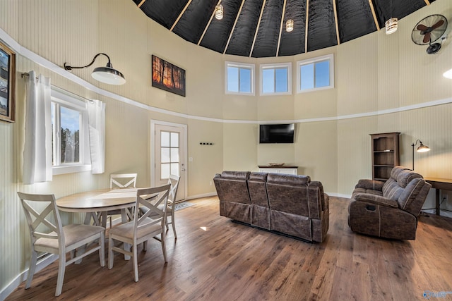living area with a high ceiling, baseboards, and wood finished floors