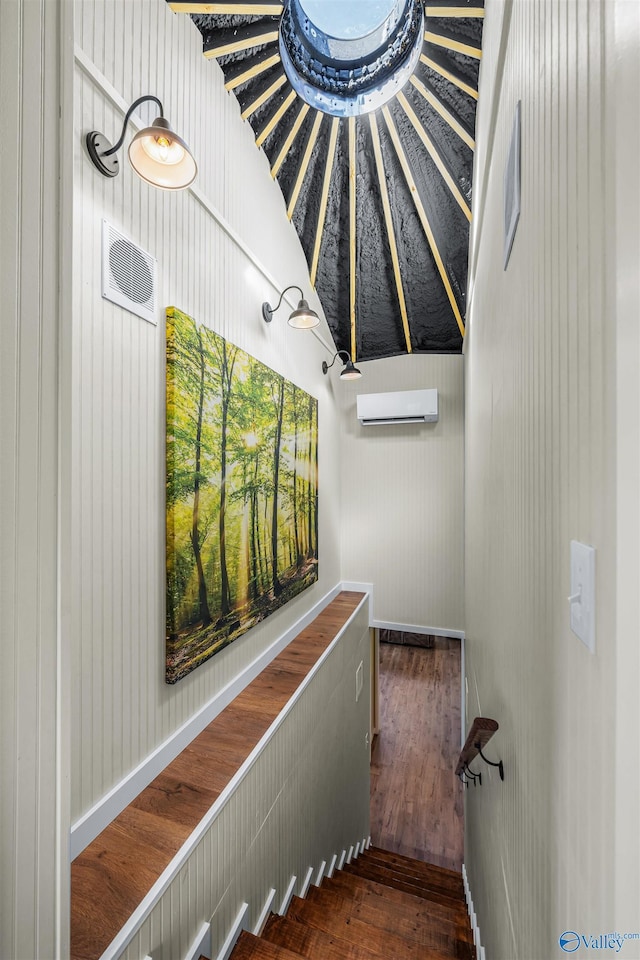 stairs featuring an AC wall unit and wood finished floors