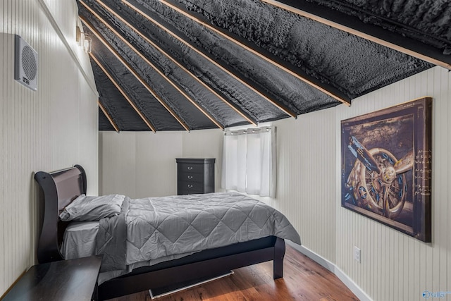 bedroom with baseboards, vaulted ceiling, and wood finished floors