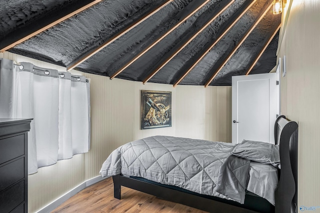 bedroom with lofted ceiling and wood finished floors