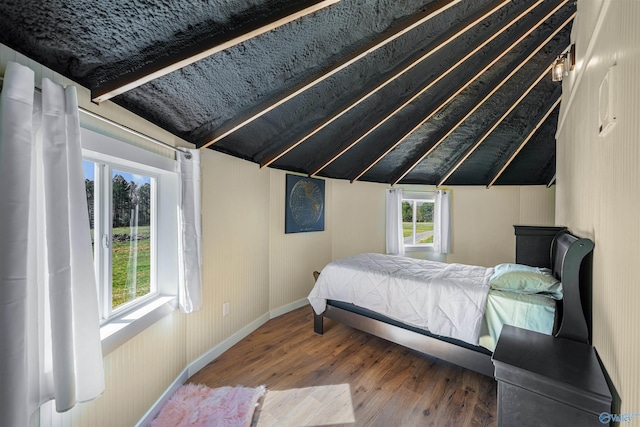 bedroom featuring vaulted ceiling with beams, baseboards, and wood finished floors