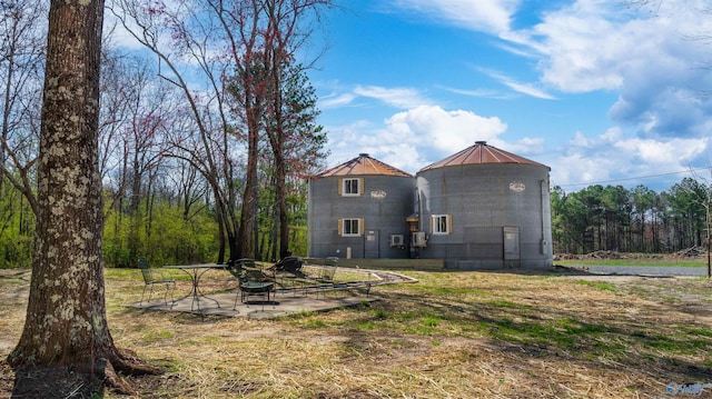 rear view of property with metal roof, a fire pit, and a patio area