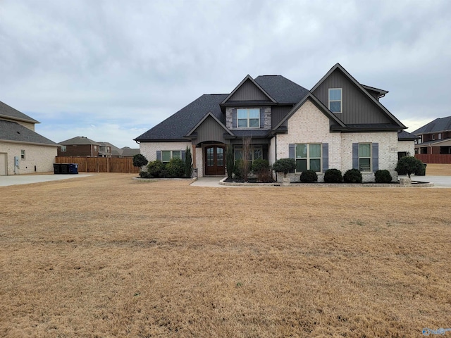 craftsman-style home featuring french doors, brick siding, fence, and a front lawn