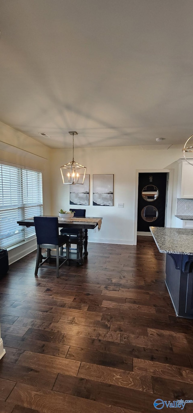 dining space with dark wood-style floors, baseboards, and an inviting chandelier