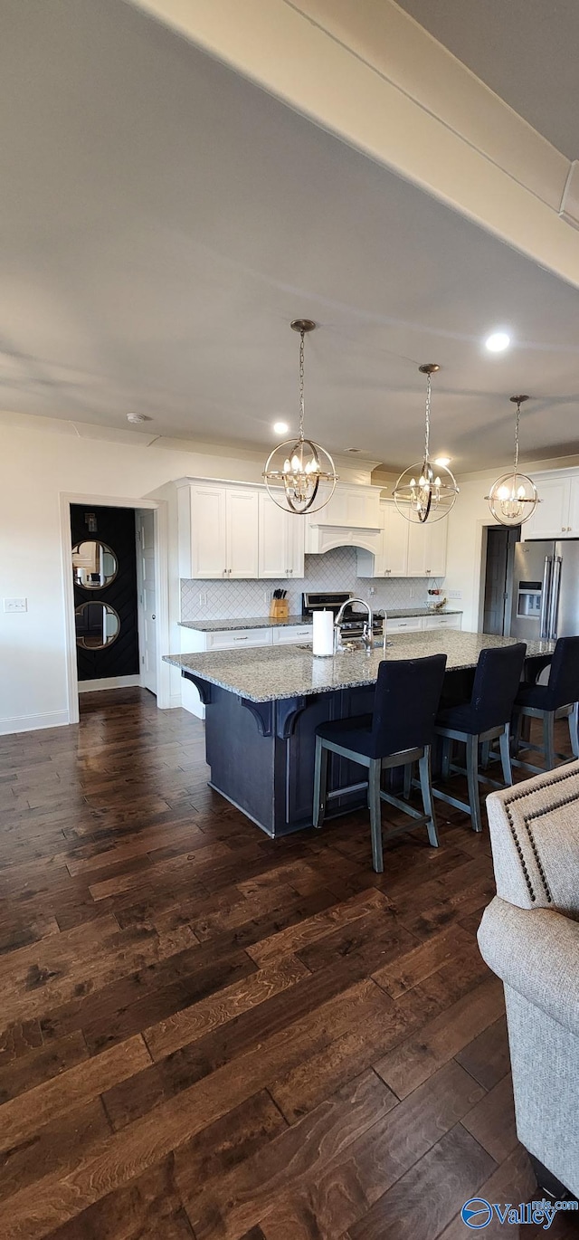 kitchen with dark wood-type flooring, a breakfast bar area, light stone counters, and decorative backsplash