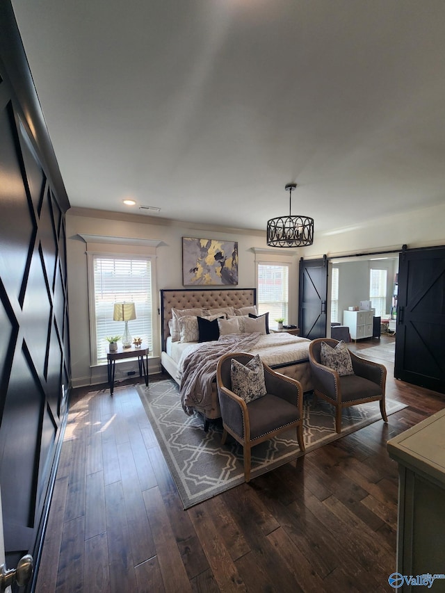 bedroom featuring a barn door, visible vents, and dark wood-type flooring