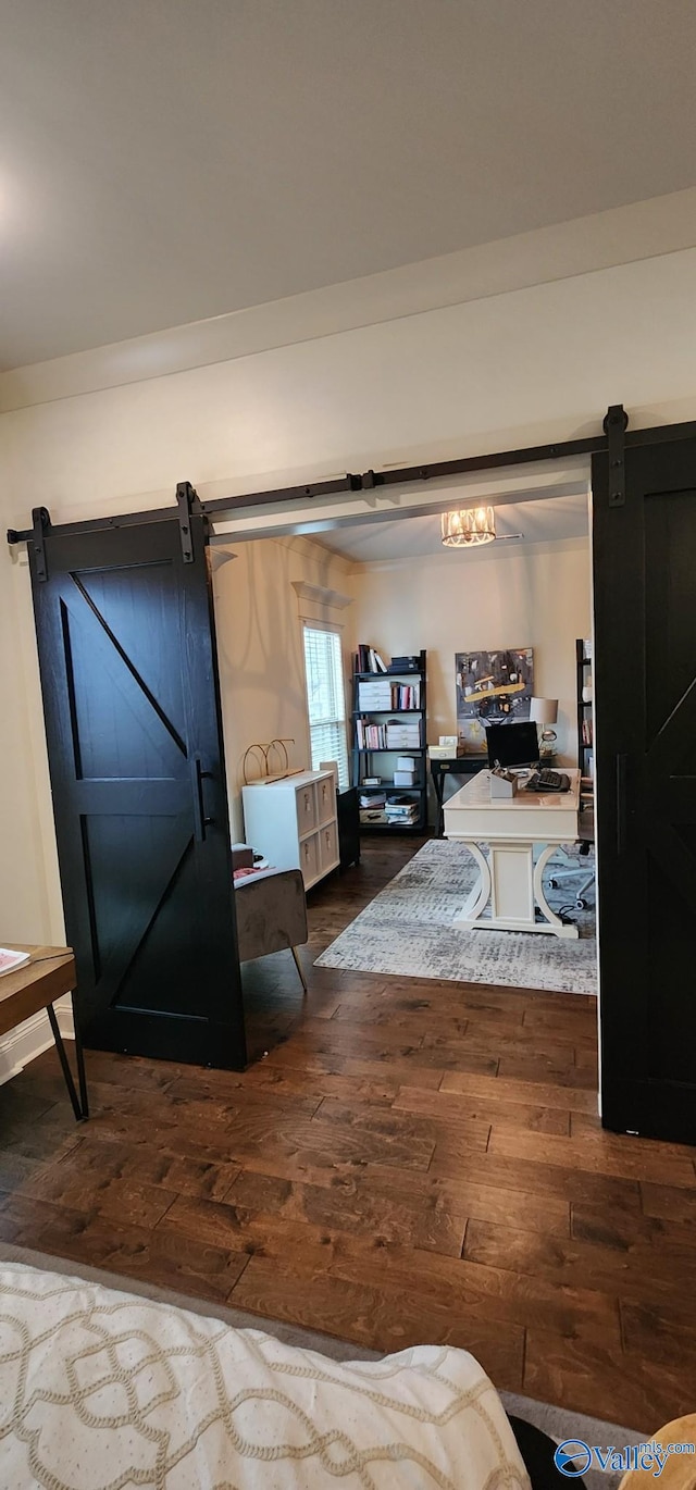 bedroom with dark wood-style floors and a barn door