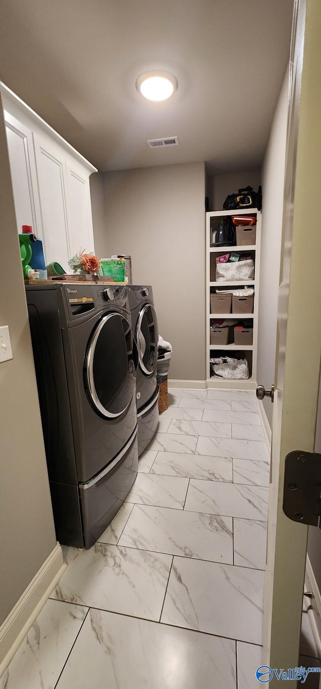 washroom featuring marble finish floor, visible vents, cabinet space, washer and dryer, and baseboards