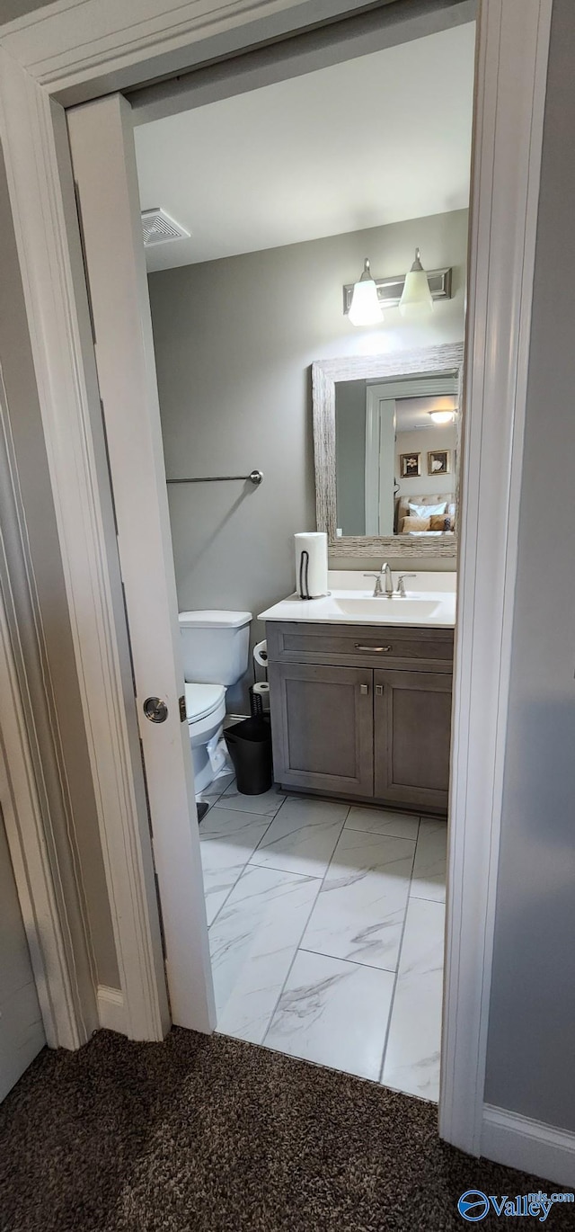 bathroom with toilet, marble finish floor, and vanity