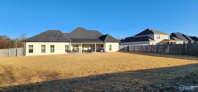 back of property with a patio area, a fenced backyard, and a lawn