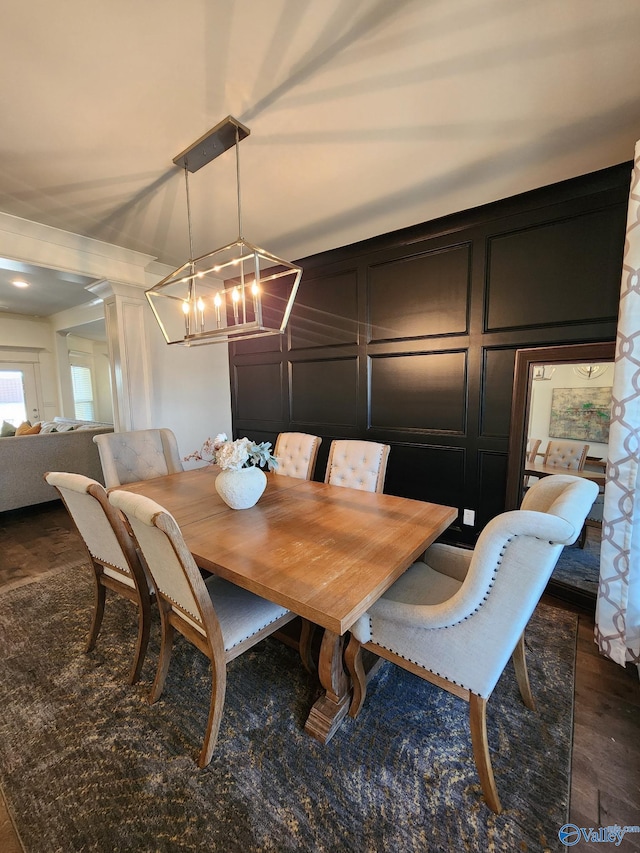 dining space featuring dark wood-style flooring, an inviting chandelier, and a decorative wall