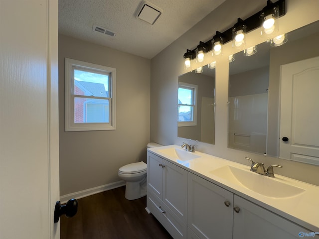 full bath featuring a textured ceiling, wood finished floors, visible vents, and a sink