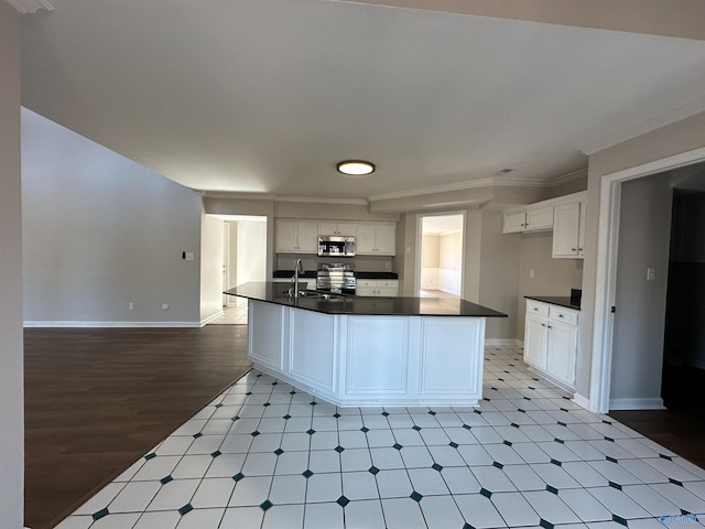 kitchen with dark countertops, light floors, ornamental molding, stainless steel appliances, and white cabinetry