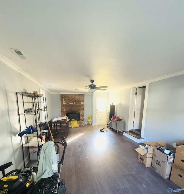 interior space with a fireplace, ceiling fan, crown molding, and dark hardwood / wood-style floors