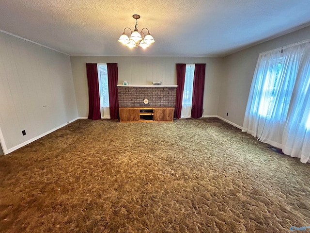 unfurnished living room featuring a textured ceiling, dark colored carpet, a chandelier, and a fireplace