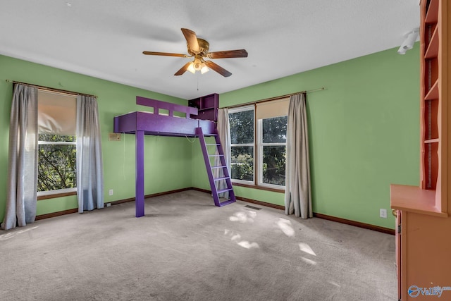 unfurnished bedroom featuring ceiling fan, a textured ceiling, and light colored carpet