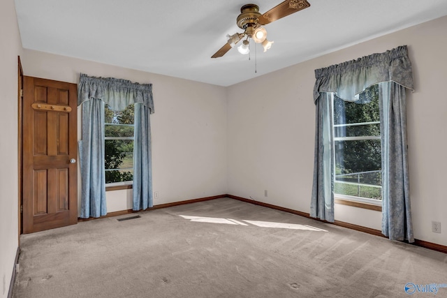 carpeted spare room featuring a healthy amount of sunlight and ceiling fan