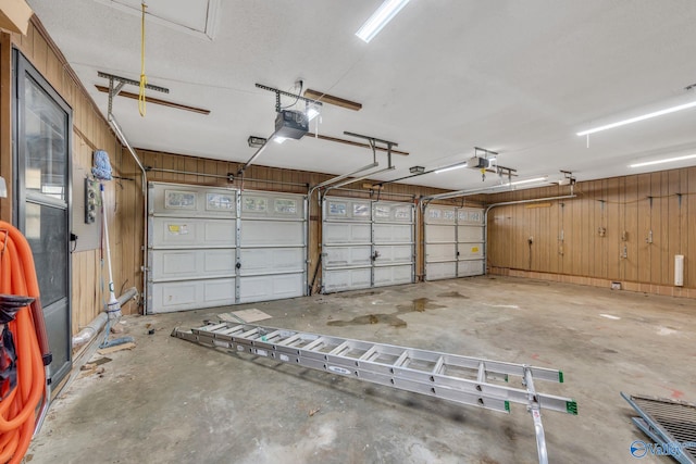 garage featuring a garage door opener and wooden walls