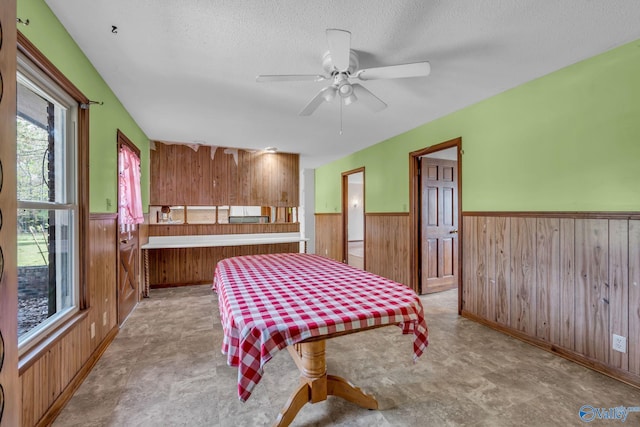 bedroom featuring wood walls, ceiling fan, and a textured ceiling