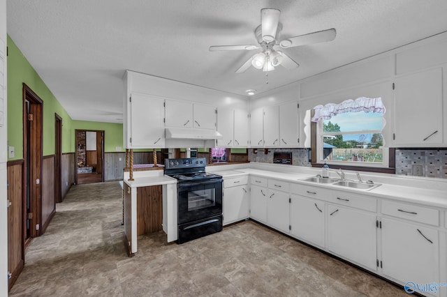 kitchen with wood walls, white cabinetry, sink, a textured ceiling, and black range with electric cooktop