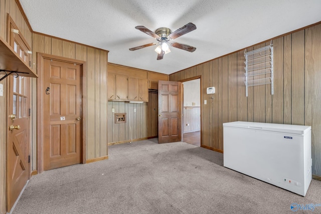 interior space featuring a textured ceiling, wood walls, and light carpet