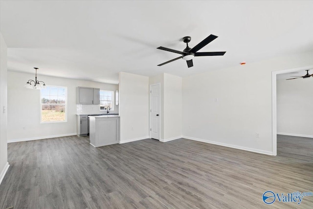 unfurnished living room featuring dark hardwood / wood-style floors and ceiling fan with notable chandelier