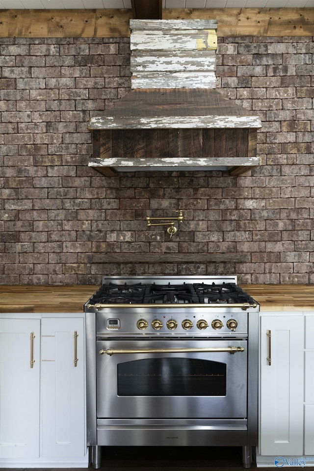 691 County Road 106, Leesburg, AL 35983 - kitchen with stainless steel stove, wood counters, brick wall, and white cabinets