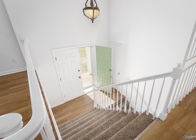 entrance foyer featuring stairs, a high ceiling, wood finished floors, and baseboards