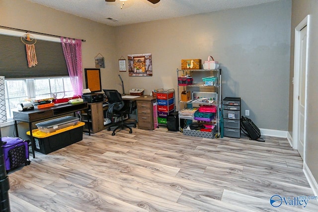 home office featuring ceiling fan, light hardwood / wood-style floors, and a textured ceiling