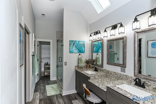 bathroom featuring hardwood / wood-style floors, vanity, vaulted ceiling with skylight, and a shower with shower door