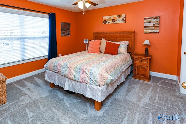 bedroom with ceiling fan, dark carpet, and a textured ceiling