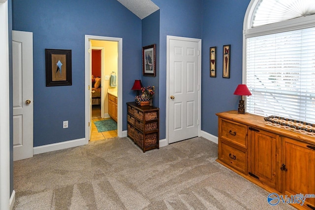 interior space with connected bathroom, light colored carpet, and lofted ceiling