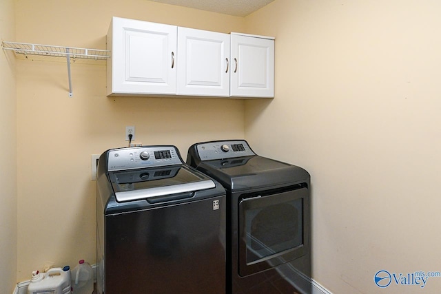 clothes washing area with cabinets and independent washer and dryer