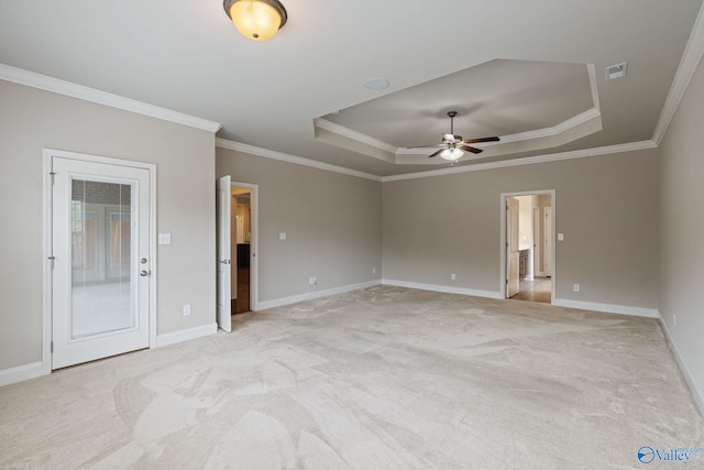 empty room featuring light colored carpet, a raised ceiling, and ornamental molding