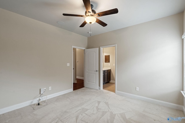 unfurnished bedroom with connected bathroom, light colored carpet, and ceiling fan