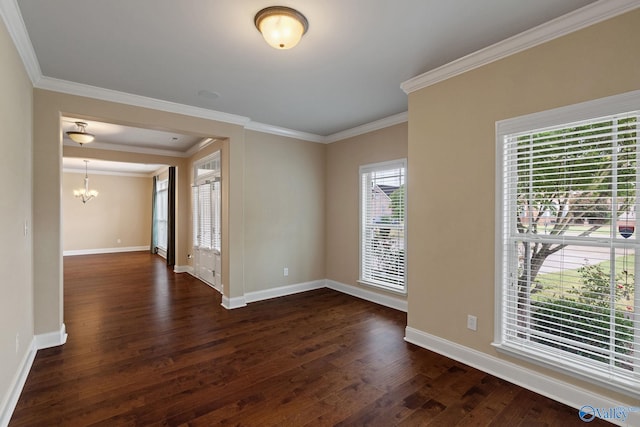 spare room featuring dark hardwood / wood-style floors, an inviting chandelier, and crown molding