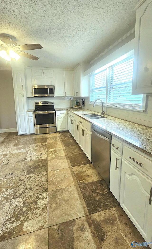 kitchen with white cabinetry, stainless steel appliances, sink, and decorative backsplash