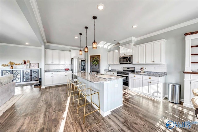 kitchen featuring a center island with sink, white cabinets, light stone countertops, a kitchen bar, and stainless steel appliances