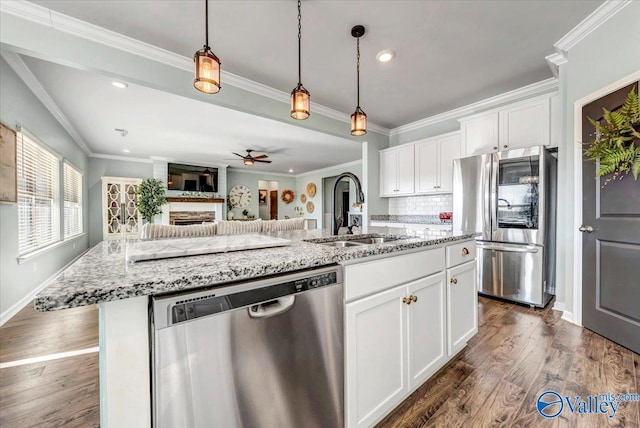 kitchen with stainless steel appliances, white cabinetry, a center island with sink, and sink