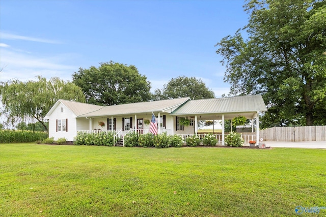 single story home featuring metal roof, fence, a porch, and a front yard