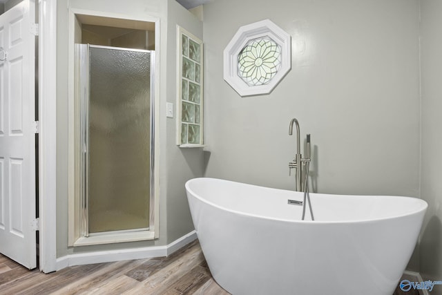 bathroom featuring plus walk in shower and hardwood / wood-style floors