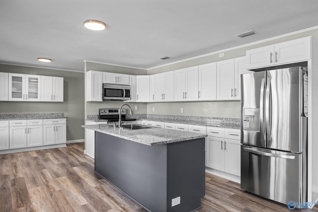 kitchen featuring appliances with stainless steel finishes, wood-type flooring, white cabinets, and light stone countertops