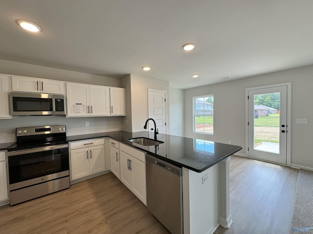 kitchen with sink, light hardwood / wood-style flooring, appliances with stainless steel finishes, kitchen peninsula, and white cabinets