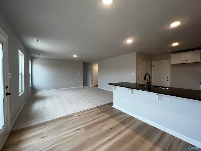 kitchen featuring white cabinetry, light carpet, and sink