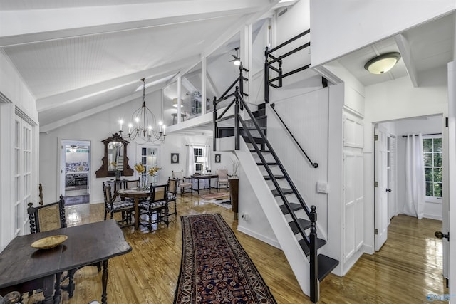 stairs featuring light hardwood / wood-style floors, a notable chandelier, and high vaulted ceiling