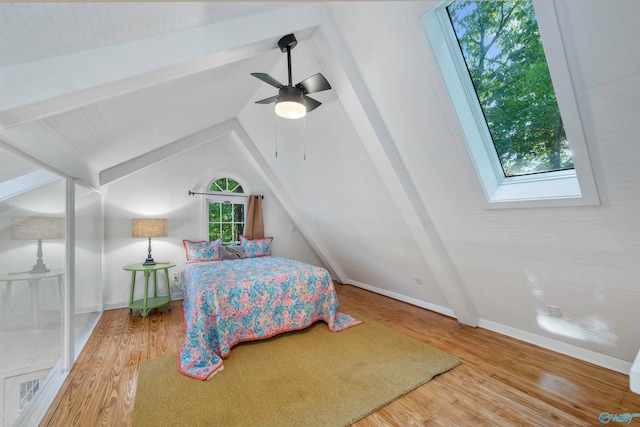 bedroom featuring ceiling fan, light wood-type flooring, and vaulted ceiling with skylight