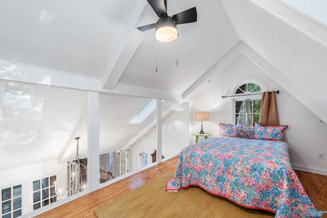 bedroom with hardwood / wood-style flooring, lofted ceiling with skylight, and ceiling fan with notable chandelier