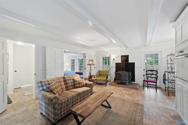 living room with a wood stove, beam ceiling, light tile patterned floors, and crown molding