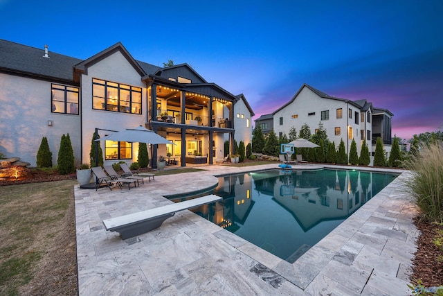 27 Watson Grande Way, Owens Cross Roads, AL 35763 - back of property at dusk featuring a patio area, a balcony, an outdoor pool, stucco siding, and ceiling fan