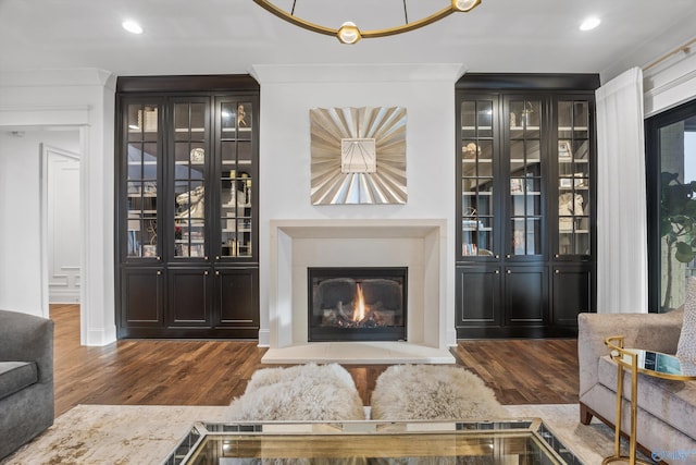27 Watson Grande Way, Owens Cross Roads, AL 35763 - living room with dark wood-type flooring, a warm lit fireplace, recessed lighting, and crown molding